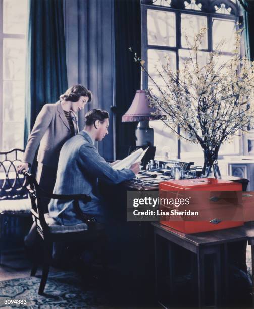 Princess Elizabeth talking to her father, King George VI whilst he goes through the Royal boxes in a study at Windsor Castle, Berkshire.