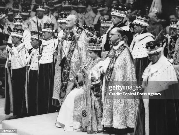 Queen Elizabeth II seated upon the throne at her coronation in Westminster Abbey, London. She is holding the royal sceptre and the rod with the dove .