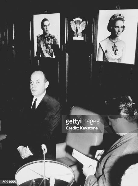 Greek Prime Minister, George Papadopoulos, speaking at a press conference, with pictures of King Constantine and Queen Anne Marie on the wall behind...