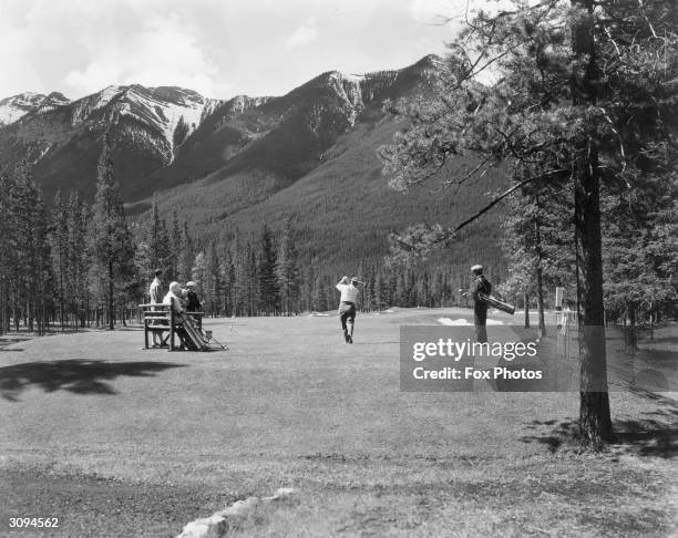 Watched by companions, a golfer tees off at the 17th hole at Banff Springs golf course.