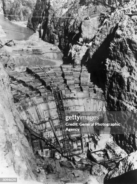 The Boulder Dam on the Colorado River under construction. A cable railway runs over it.