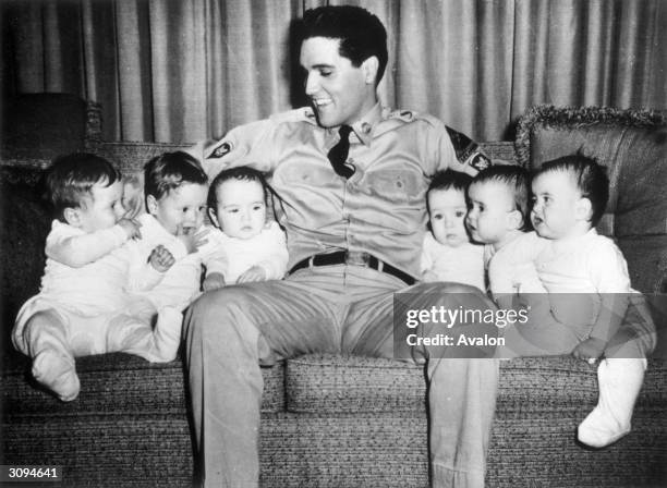 Rock 'n' roll singer Elvis Presley with six babies during the making of the film 'GI Blues', in which he plays a soldier. Due to employment laws in...