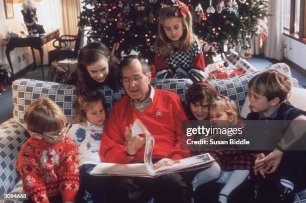 American statesman George Bush, the 41st President of the United States, reading a Christmas story to his grandchildren on Christmas Eve at the White...