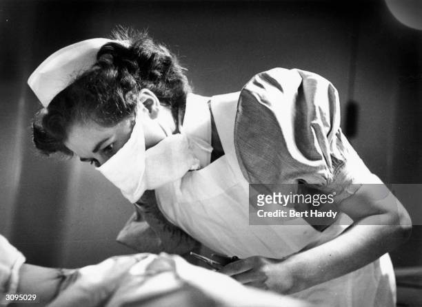 Student nurse Dorothy Norris tends a patient on the surgical ward of the London Hospital. Original Publication: Picture Post - 6780 - I Want To Be A...