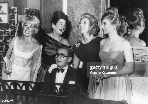American composer Irving Berlin performing after receiving a Milestone Award from the Screen Producers Guild. Behind him are Ginger Rogers, Rosalind...