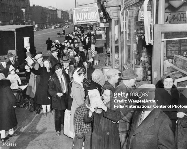 Woman in a long queue outside a shop in America holds up a bag of Jack Frost sugar.