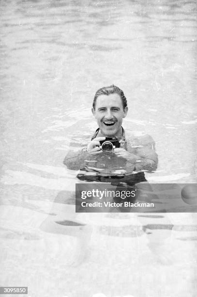 English racing driver Graham Hill using an underwater camera in a swimming pool at Monaco before the grand prix.