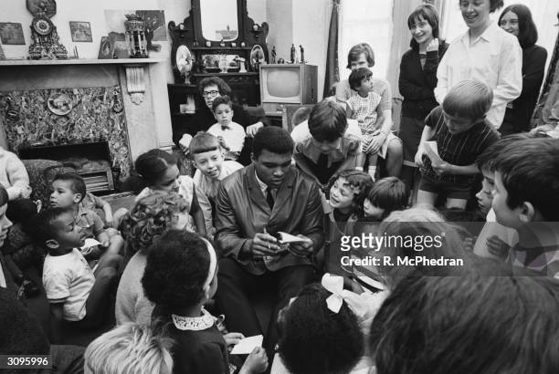 World heavyweight boxing champion Cassius Clay signs autographs during a visit to the London Free School children's play group and families' group at...