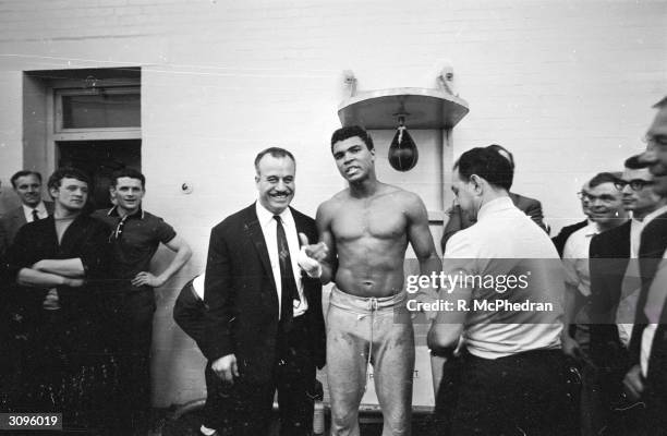 World heavyweight boxing champion Muhammad Ali, has his hands bandaged by his manager Angelo Dundee before the day's training session at the...