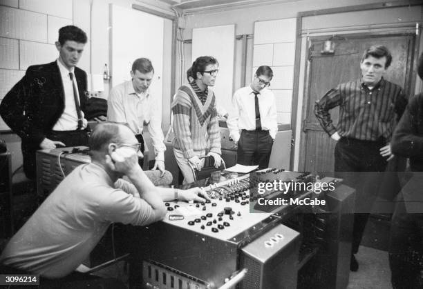 Cliff Richard in a stylish sweater, listens as the producer and recording technician makes some adjustments in a recording studio of EMI in London....