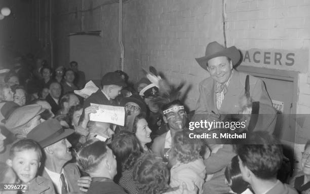 American singing cowboy Tex Ritter aka Woodward Ritter , star of many B feature films, signs autographs for a crowd of fans.