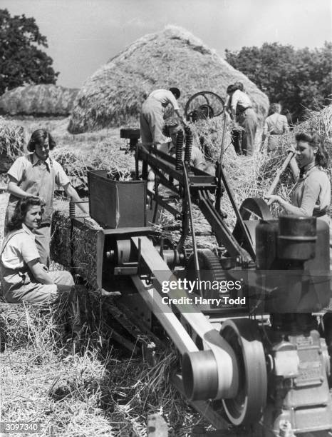 Group of Land Girls using a baling machine during a demonstration of their efficiency in West Suffolk.