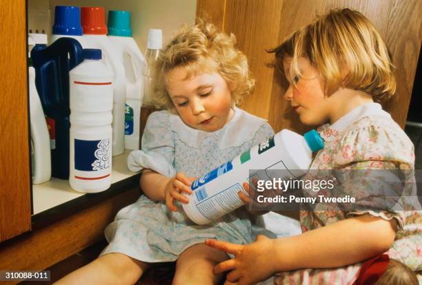 two girls (2-3) in home, examining bottle of bleach - lixívia imagens e fotografias de stock
