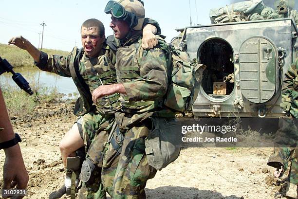 Marines from Task Force Tarawa take care of their wounded while being pinned down by intense enemy fire March 23, 2003 in the southern Iraqi city of...