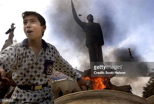 An Iraqi boy cheers as a statue of ousted Iraqi President Saddam Hussein is set ablaze during an impromptu celebration on the streets April 12, 2003...