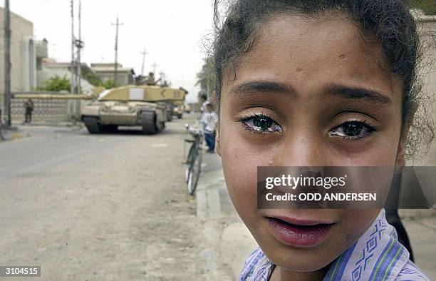 Young Iraqi girl cries as a British Challenger tank moves in on the Baath party office in Basra 08 April 2003. British and coalition forces took...