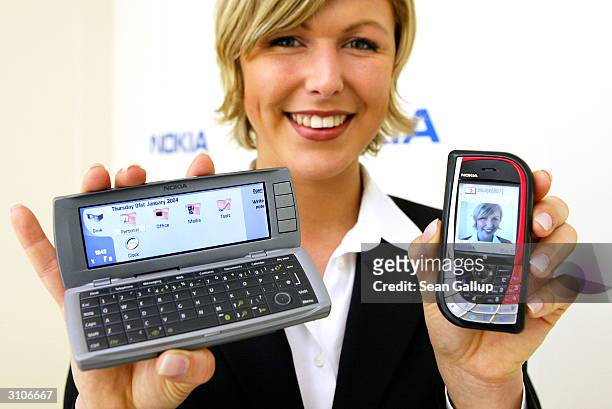Model holds the new Nokia 7610 mobile phone and the Communicator 9500 at the CeBIT technology trade fair March 18, 2004 in Hanover, Germany. This...