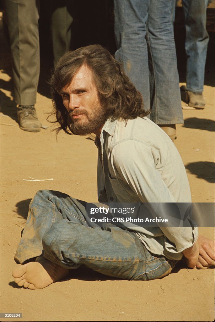 American actor Steve Railsback sits on the ground with his hands ...