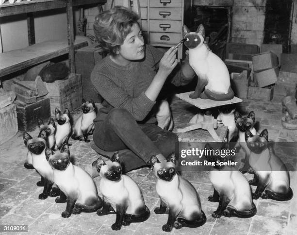 Jennifer Winstanley of Wimbledon painting the faces on Siamese cats at Kensington potteries.