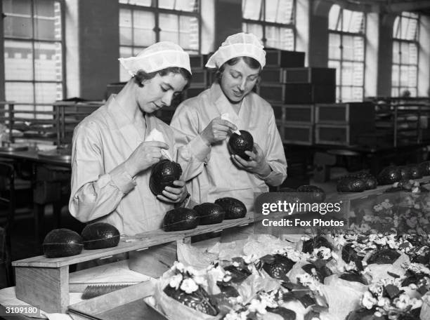 Two women at the Cadbury's chocolate factory in Bournville, in the West Midlands join together chocolate Easter egg halves.