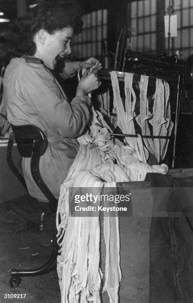 Worker in a Liverpool nylon stocking factory operates a 'linking' machine. In post-war Britain there is a shortage of operators of this type of...