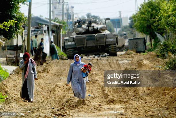 Al-MOGHRAGA VILLAGE, GAZA STRIP A Palestinian family, who are relatives of Hamas military leader Maysara Hassan, walk in front of an Israeli tank...