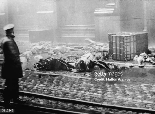 Policeman stands in the street, observing charred rubble and corpses of workers following the Triangle Shirtwaist Company fire in New York City,...