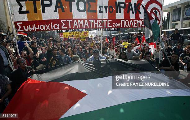 Greek and Palestinian protesters shout anti-US slogans during an anti-US war in Iraq to mark the one year anniversary of the start of the Iraq war in...