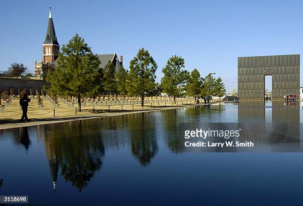 Visitors walk past the reflections from a memorial wall with 9:03 etched into it, the time of the Oklahoma City bombing, on March 21, 2004 In...