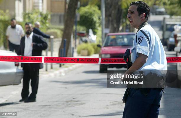 An Israeli policeman stands guard at the scene where a man wielding an axe attacked three passers-by outside an army base on March 22, 2004 near Tel...