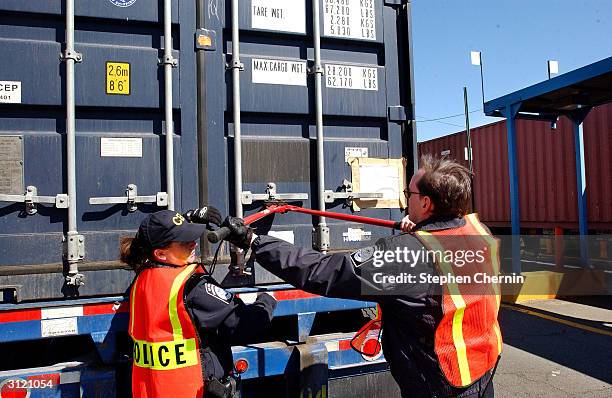 Customs inspectors cut off a lock as they prepare to examine the contents of a shipping container at the docks March 22, 2004 in Jersey City, New...