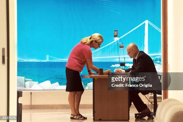 Two employees speak to one another in a corridor of the "Stretto di Messina" company in front a simulation photo of the planned bridge over the...