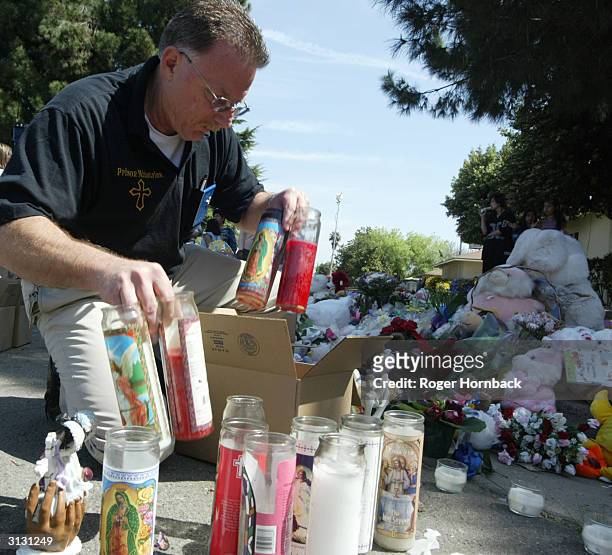 Fresno City Police Chaplain Ed Crain fills a box with candles from the memorial in front of Marcus Wesson's house March 25, 2004 in Fresno,...