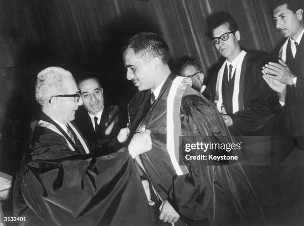 The Dean of Jordan University helps King Hussein of Jordan with his gown during a royal visit to the University, 21st April 1965.