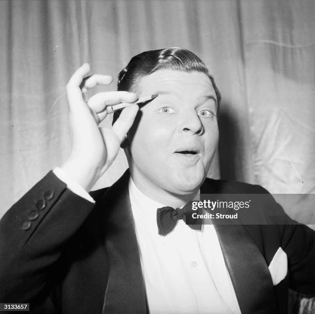 English comedian, Benny Hill , originally Alfred Hawthorne Hill, applying make-up to his eyes.
