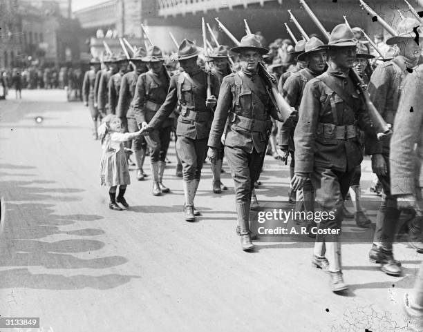 Little girl has her hand shaken by an American soldier as his troop parade through the streets of London.