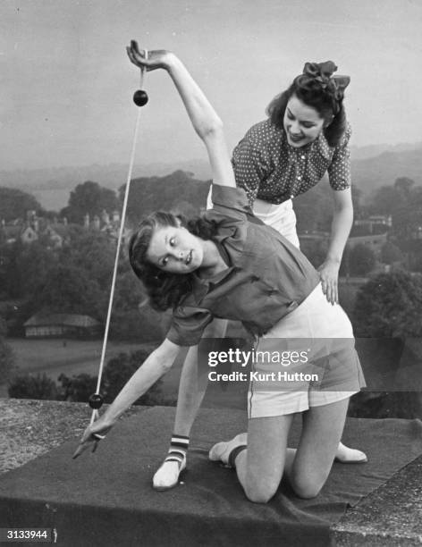 Pamela Minchin and April Stride demonstrate the new 'lithe-line' exercises promoted by Helena Rubinstein on the roof of a block of flats in London....