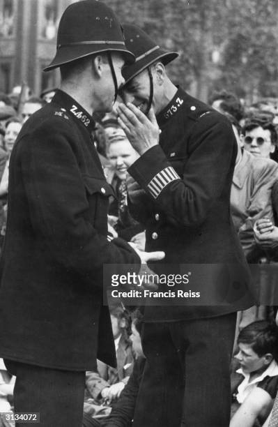 Policeman shares a giggle with a colleague during the Victory Day parades in London, on the first anniversary of Victory in Europe at the end of...