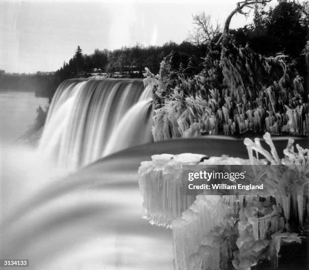 Niagara Falls in winter, seen from Goat Island. Luna Island stands in the middle of the cascade, known as the American or Rainbow Falls, and Prospect...