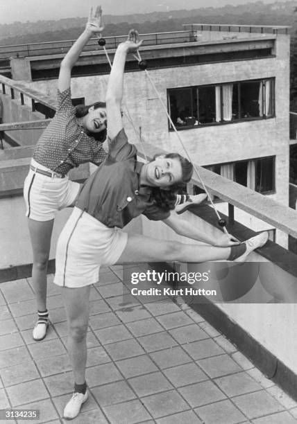 Pamela Minchin and April Stride demonstrate the new lithe-line exercises promoted by Helena Rubinstein on the roof of Highpoint, a block of flats in...