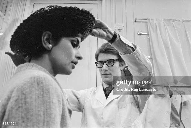 French fashion designer Yves Saint-Laurent working with a fashion model at his fashion house in Paris.