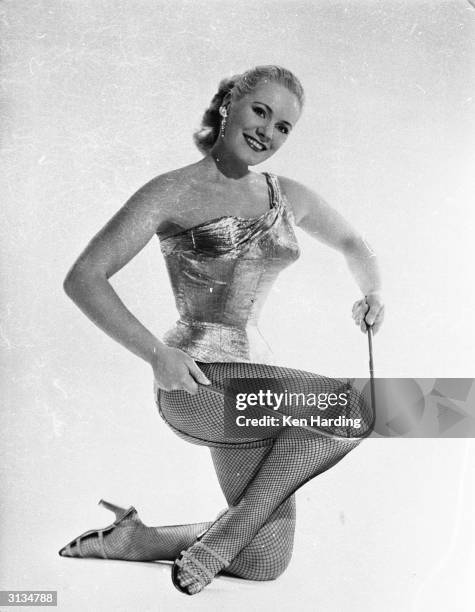Glamorous strongwoman and model Joan Rhodes of Hampstead, north London, bends an iron bar with ease.