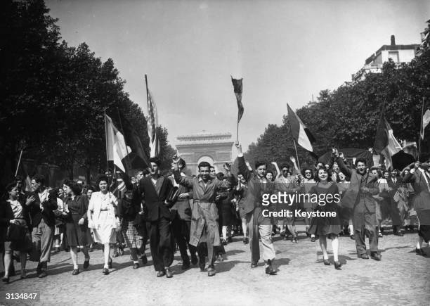 Crowds on the Champs Elysees celebrate Victory in Europe at the end of World War II with a joyful procession.