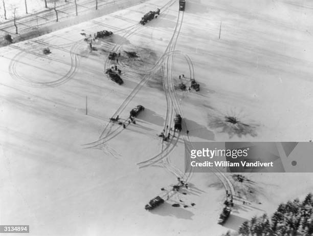 Military vehicles circumvent shell craters in a snowy field in the Ardennes battle sector, bringing supplies and ammunition to the front.