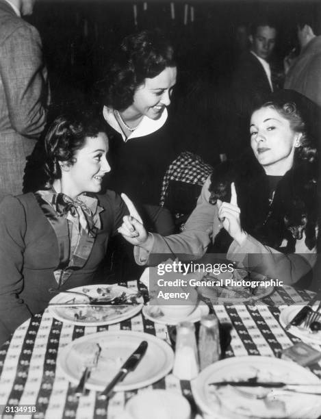 British actress Olivia de Havilland in a restaurant with her sister Joan Fontaine and American actress Margaret Lindsay.