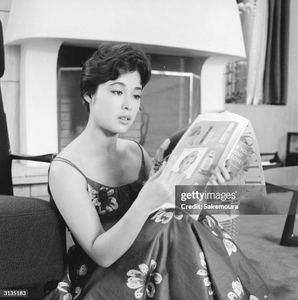 Japanese film actress Ayako Wakao relaxing at her home with a copy of Vogue.