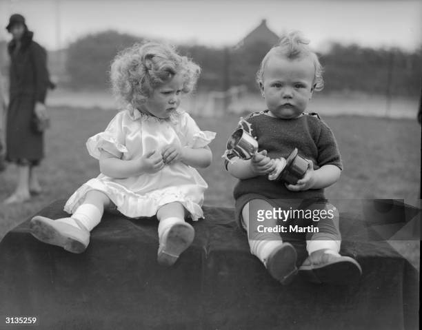 Twins Michael and Mary Kerby fail to convey any enthusiasm upon winning a trophy in a Baby Show at Ruislip, Middlesex.