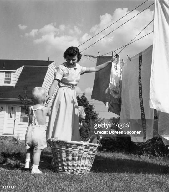 Mary Eileen Lewis hangs out the family washing helped by her baby son Bobby. 5 years ago Mary's husband Robert was a regular commander of The Enola...