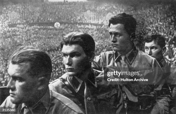 Nazi party members listening to a speech by Hitler.
