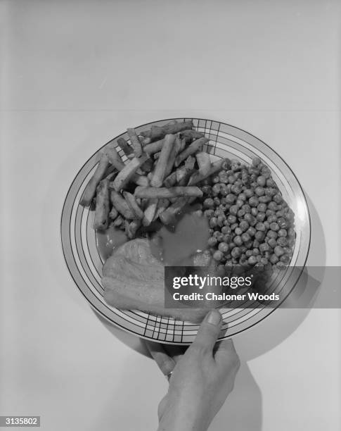 Meal of bacon, chips, peas and a dollop of sauce served on a patterned plate.